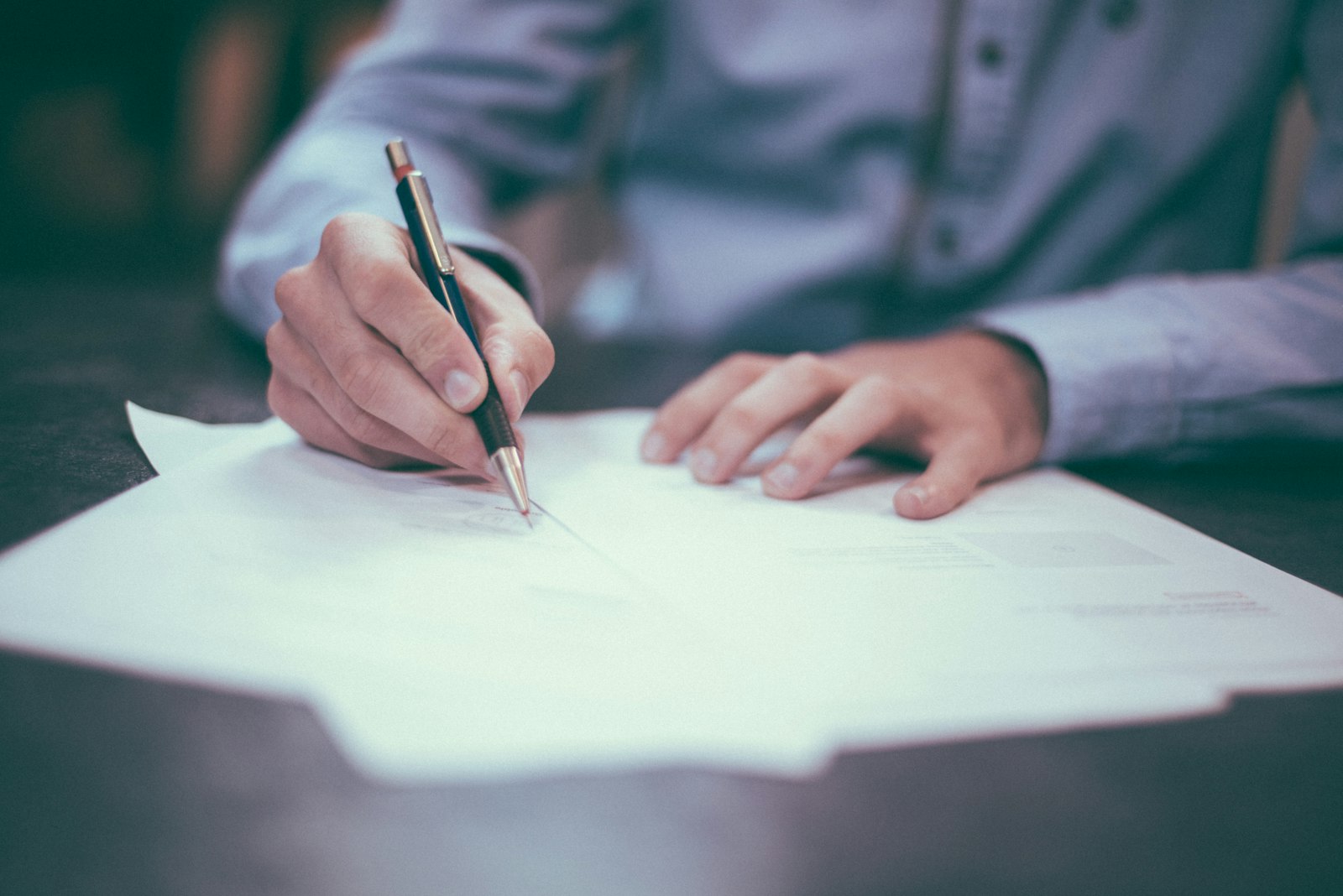 Personne signant des documents financiers sur un bureau